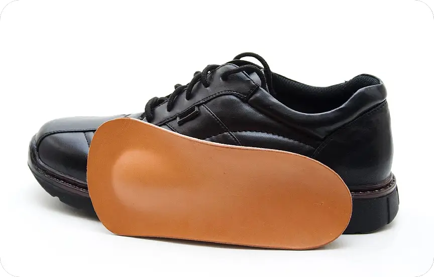 Black leather shoe with a brown orthotic insole beside it.