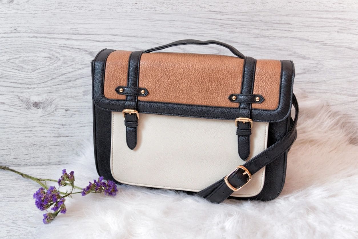 Stylish brown and cream leather satchel with buckles and shoulder strap.